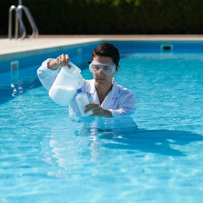 Personne ajustant les niveaux de pH dans une piscine avec des produits chimiques