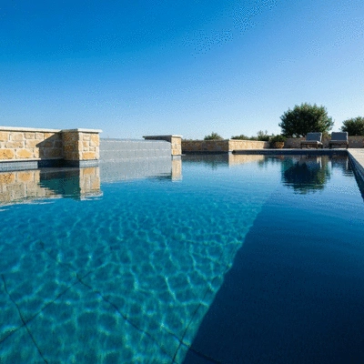 Luxurious modern swimming pool with integrated LED lighting and natural stone elements, reflecting a clear blue sky, no text, no words, no typography, clean image