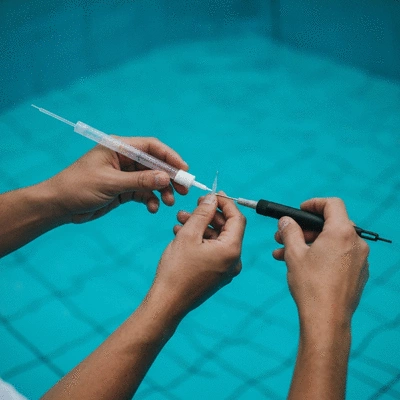 Personne ajustant les niveaux de pH et de chlore dans une piscine avec des outils de test
